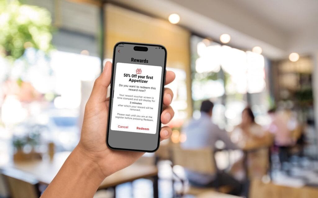Customer using a restaurant loyalty rewards app on a smartphone to redeem a promotional offer.