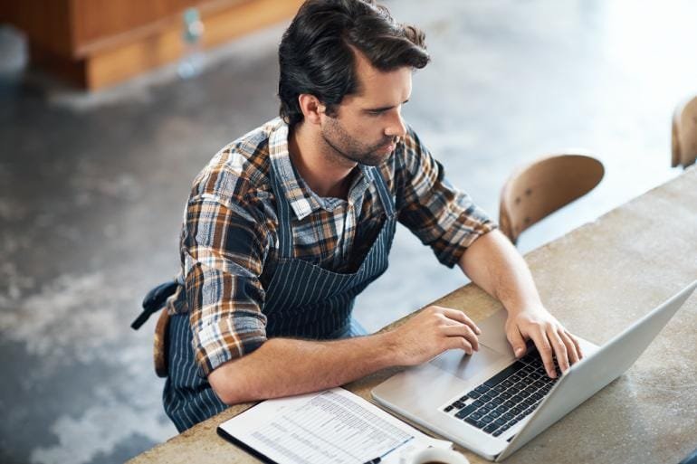 Restaurant owner creating an email marketing campaign on a laptop.